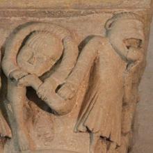 Capitel en la iglesia romanica de San Juan Bautista de Grandson, en Suiza, con la representación de un monje tirando la lengua